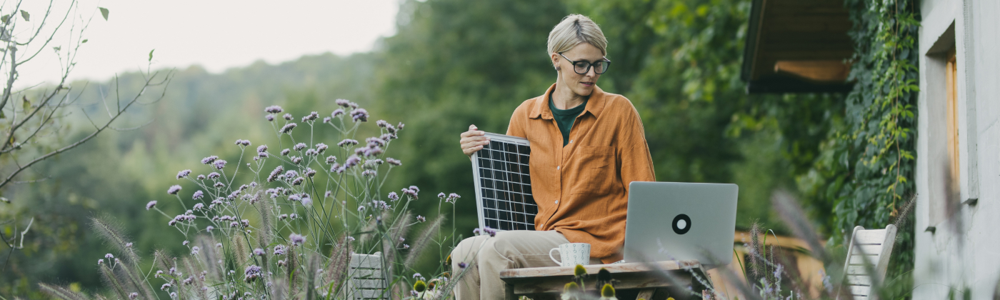 woman siting with solar panel and laptop on the nature